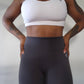 Woman modeling active-wear brand Sweat or Sparkle Athletics White Cross-Back Sports Bra and Gunpowder Gray Scrunch Leggings.