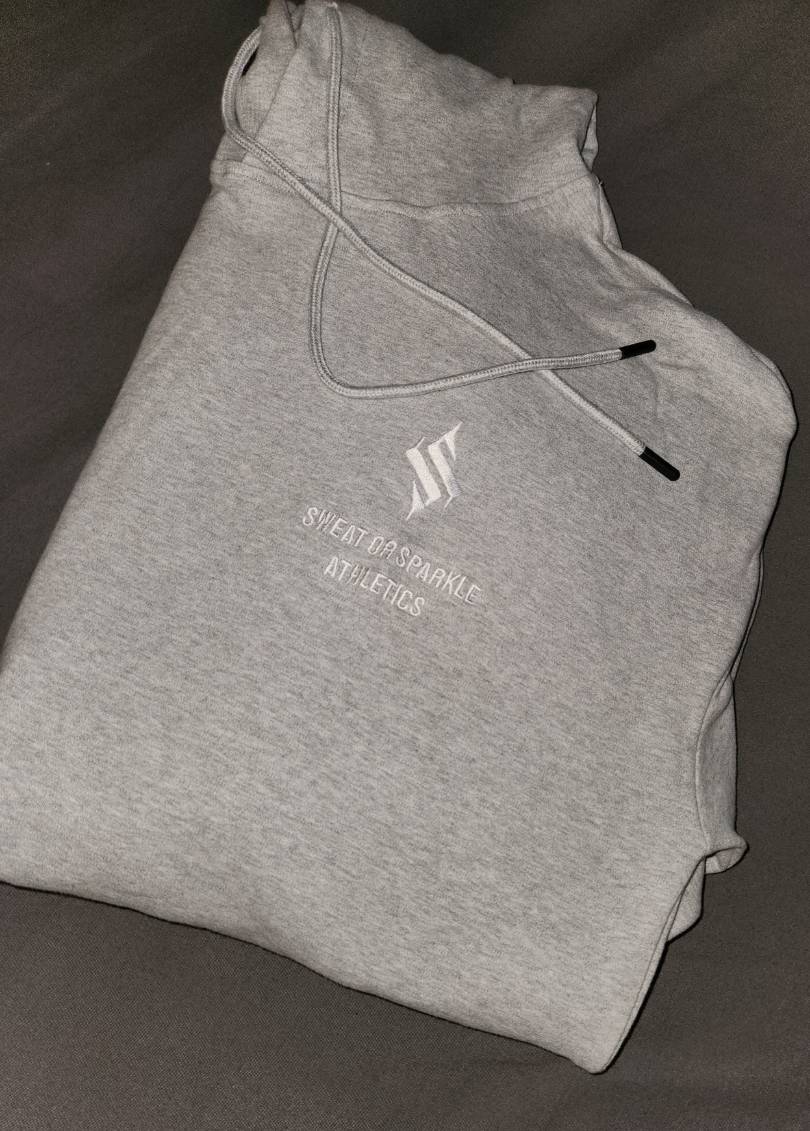 Image of active-wear brand Sweat or Sparkle Athletics Glacier Gray Hoodie folded on a gray blanket.