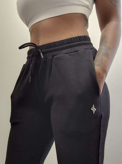 Woman modeling active-wear brand Sweat or Sparkle Athletics White Sports Bra and Black Sweatpants.