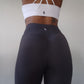 Woman modeling active-wear brand Sweat or Sparkle Athletics White Cross-Back Sports Bra and Gunpowder Gray Scrunch Leggings.